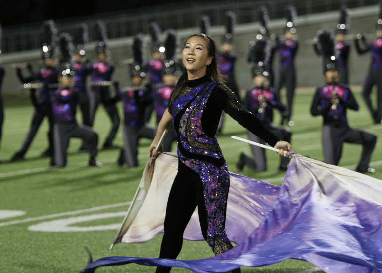 color guard performer on football field with band in background